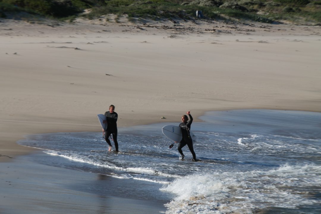 Two men surfing in cold water conditions